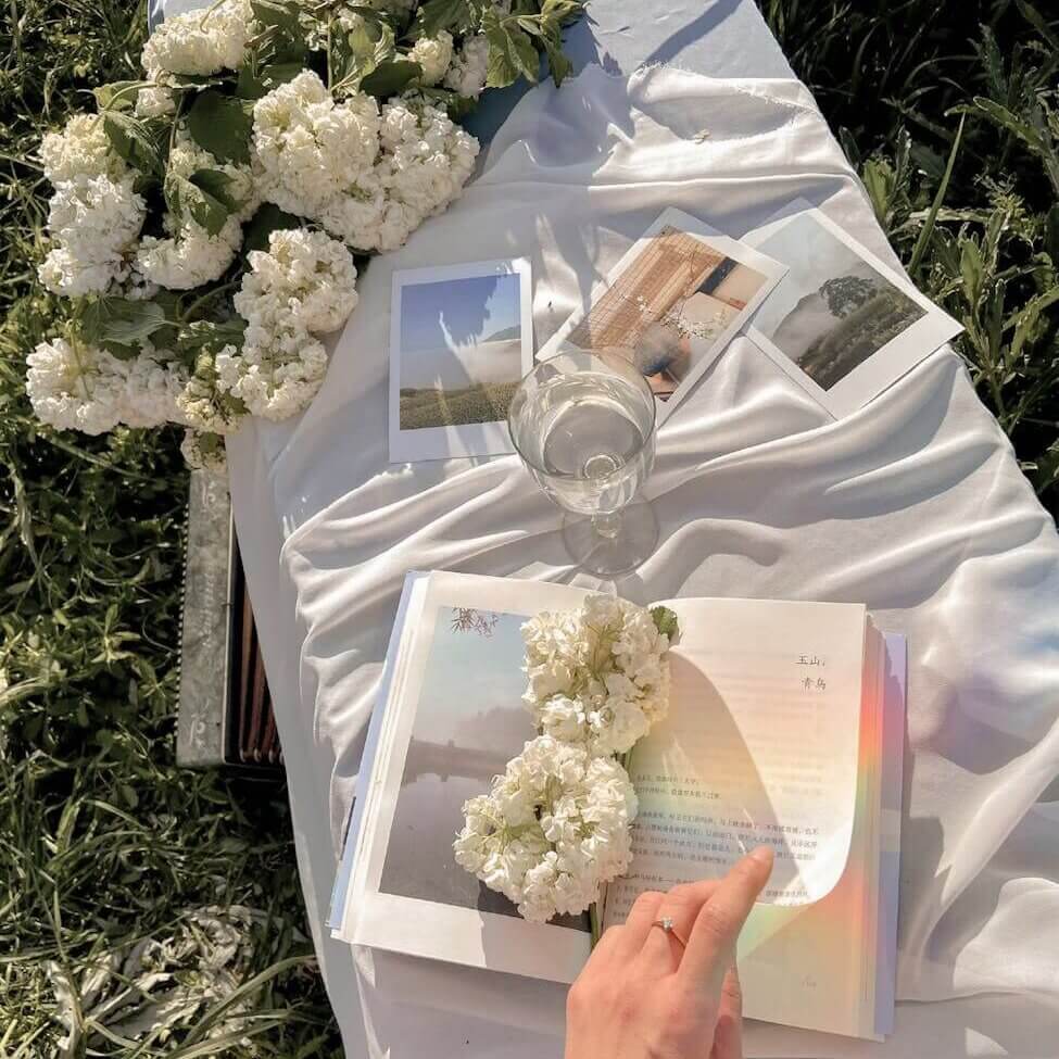 crop woman reading book on grass