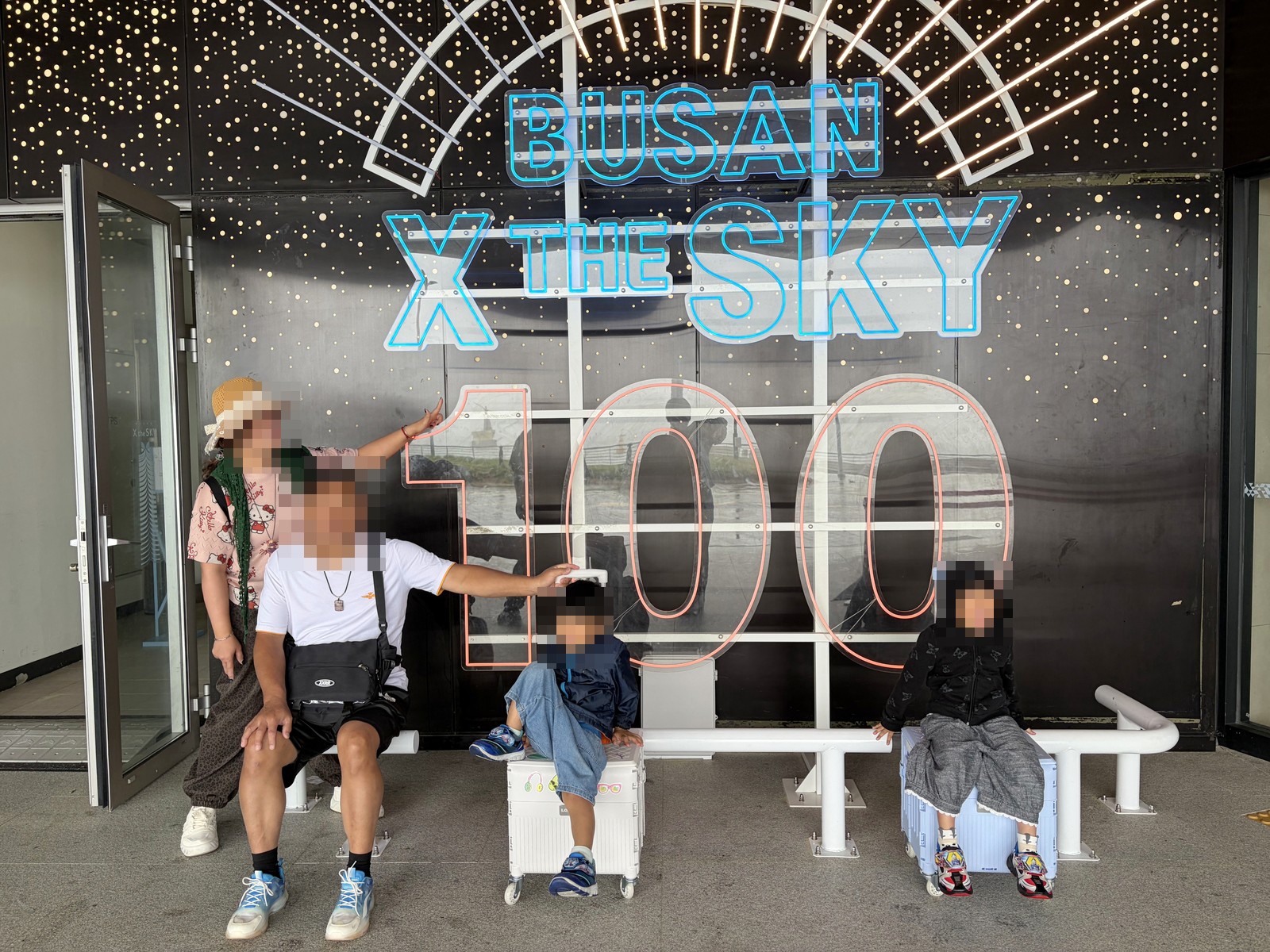 一家人坐在BUSAN X the SKY 100樓燈光裝置前的長椅合照
