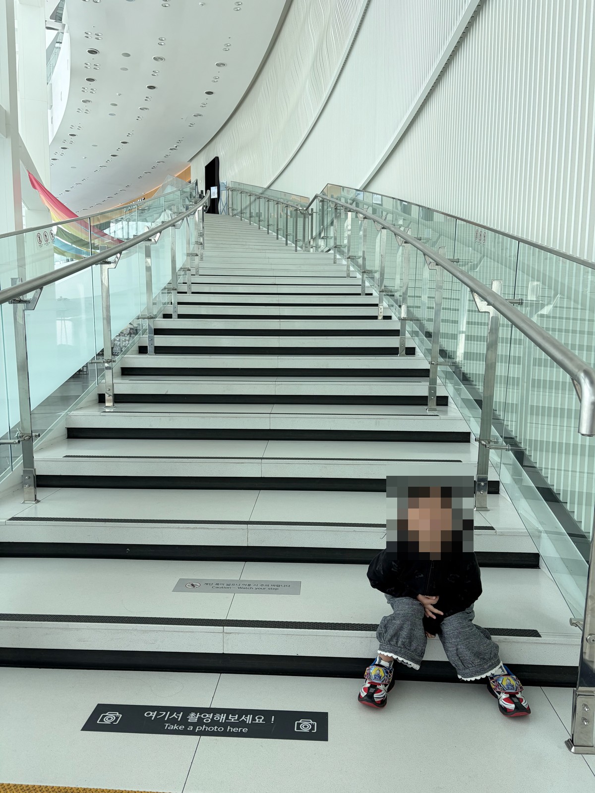 孩子坐在BUSAN X the SKY展望台的白色階梯上