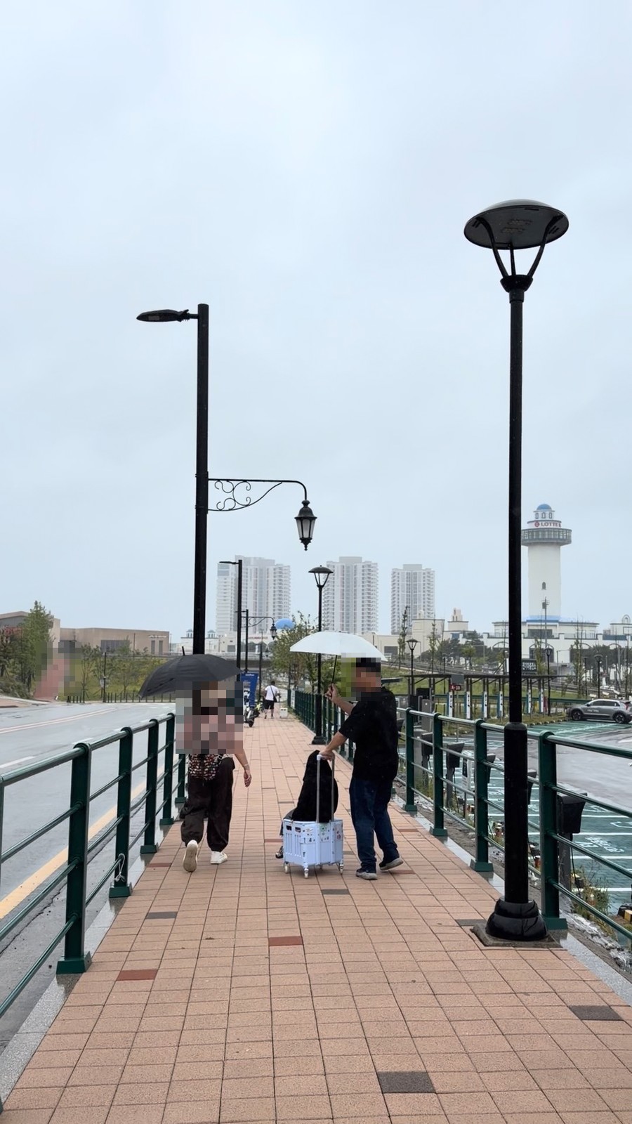 下雨天撐傘走在釜山樂天世界旁的海邊步道