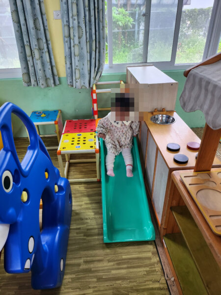孩子在成功親子館的綠色小溜滑梯上準備滑下來