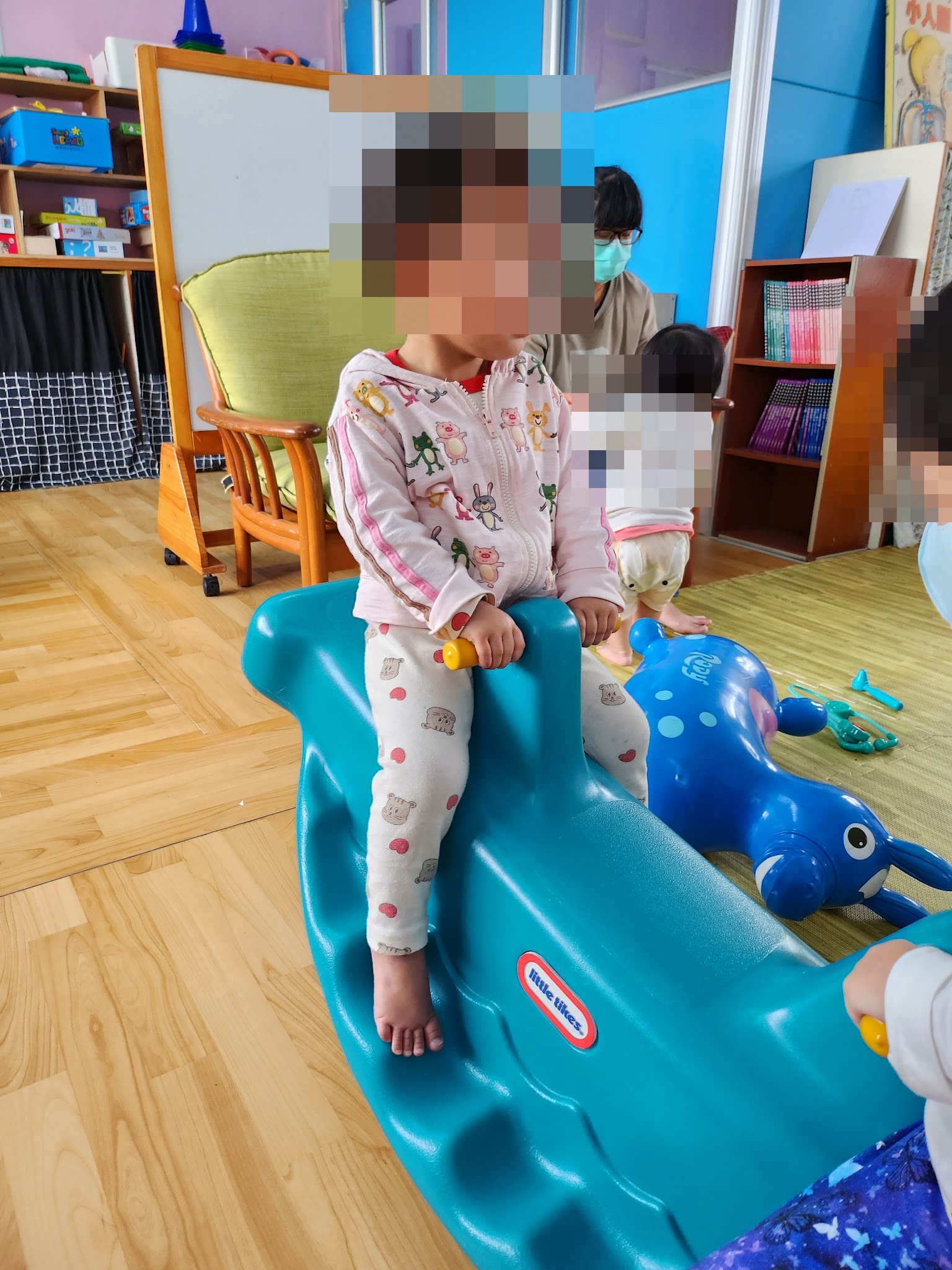 孩子坐在成功親子館的藍綠色搖搖馬上