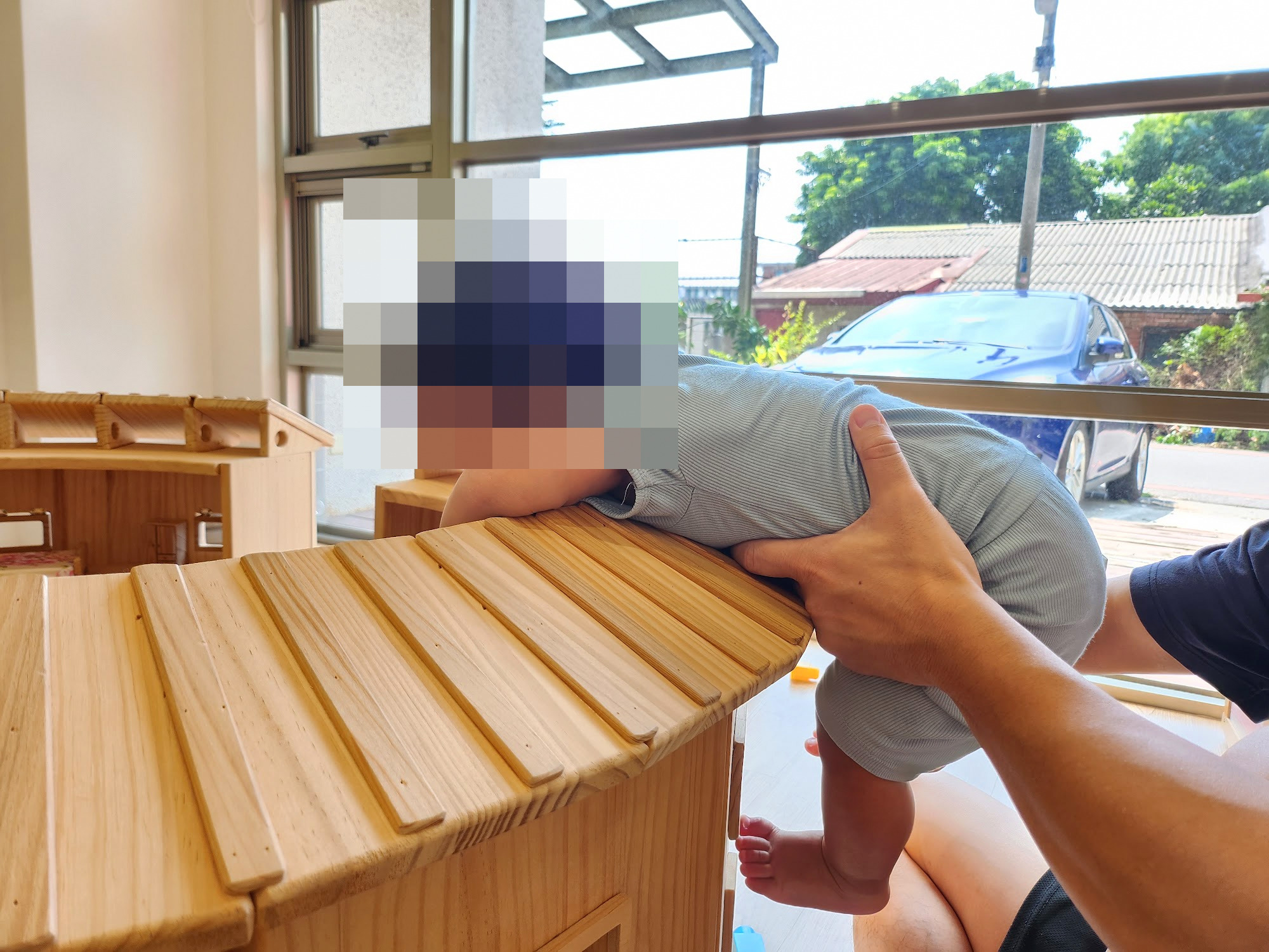 孩子在大人扶著下攀爬木頭遊戲屋