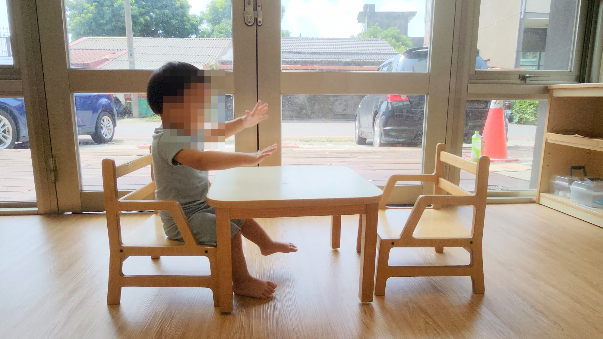 孩子坐在窗邊的木頭小桌椅