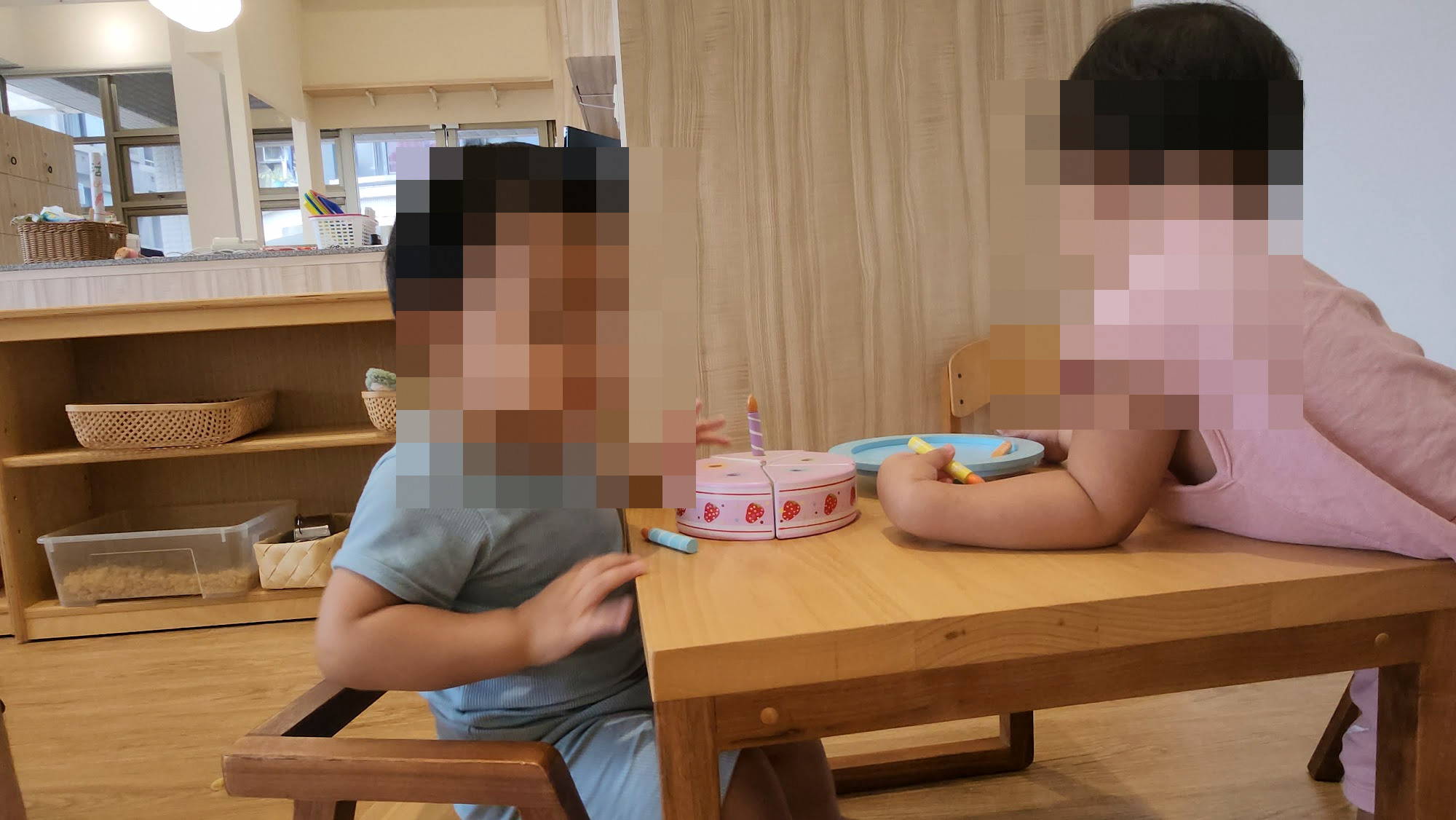 孩子坐在小椅子上和姊姊一起玩扮家家酒