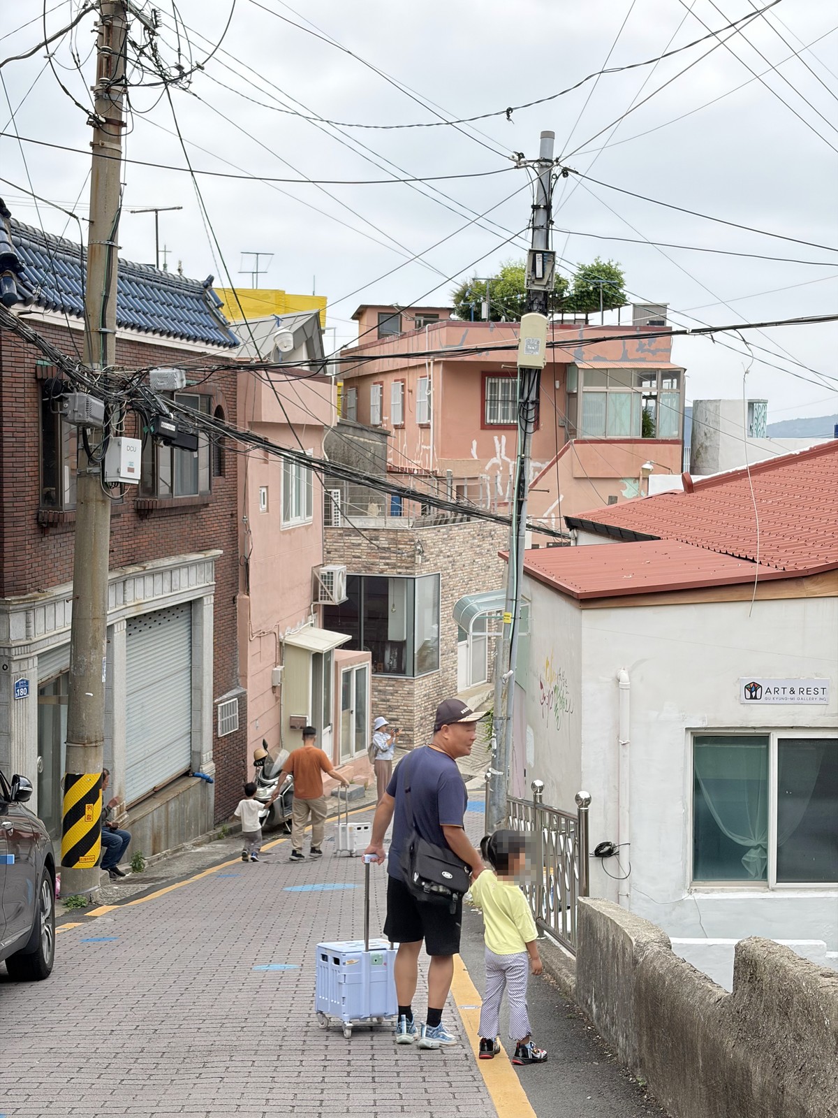 一家人推著折疊推車走在甘川文化村的坡道巷弄