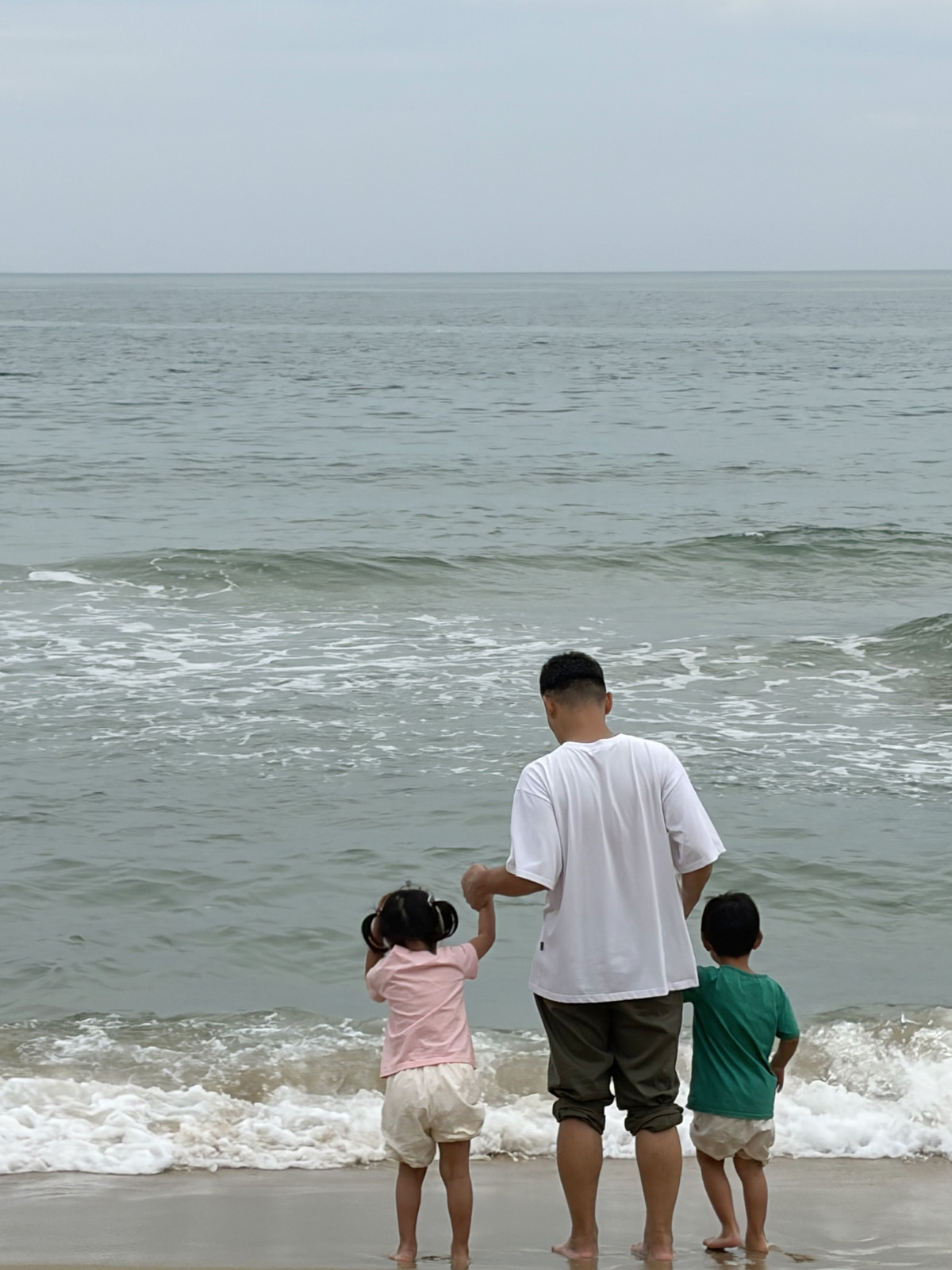 爸爸牽著芮和樂在海雲台海水浴場踩浪