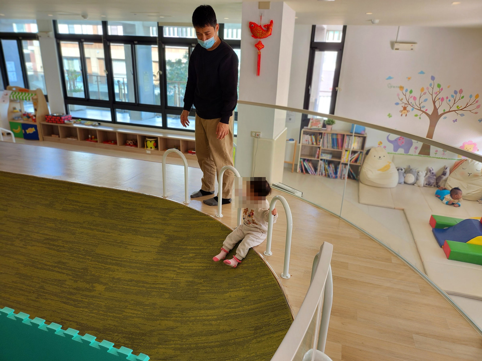 大人陪孩子在北區親子館草地造型區走動(孩子臉部已打馬賽克)