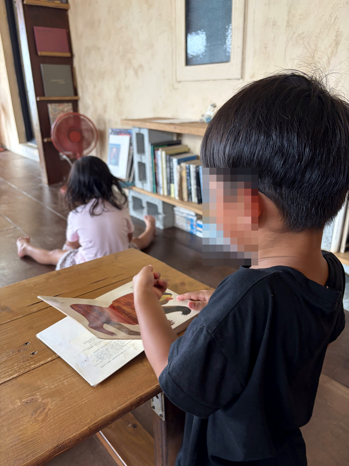兒子在冰果店裡看繪本，姐姐坐在地上看書