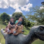 芮和樂騎在九九峰動物樂園的恐龍模型上