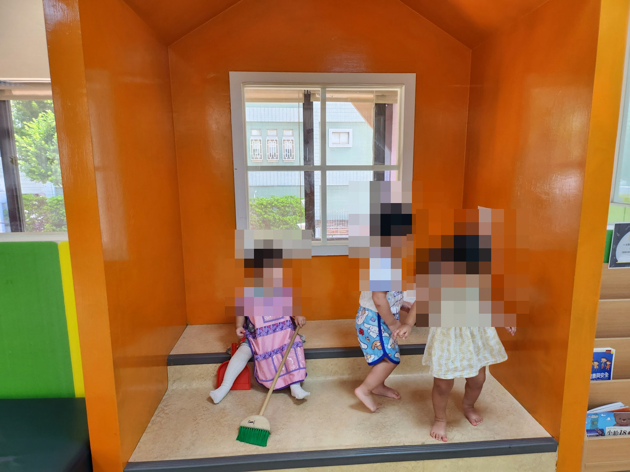 橘色小房子造型的扮演區,孩子拿著掃把玩