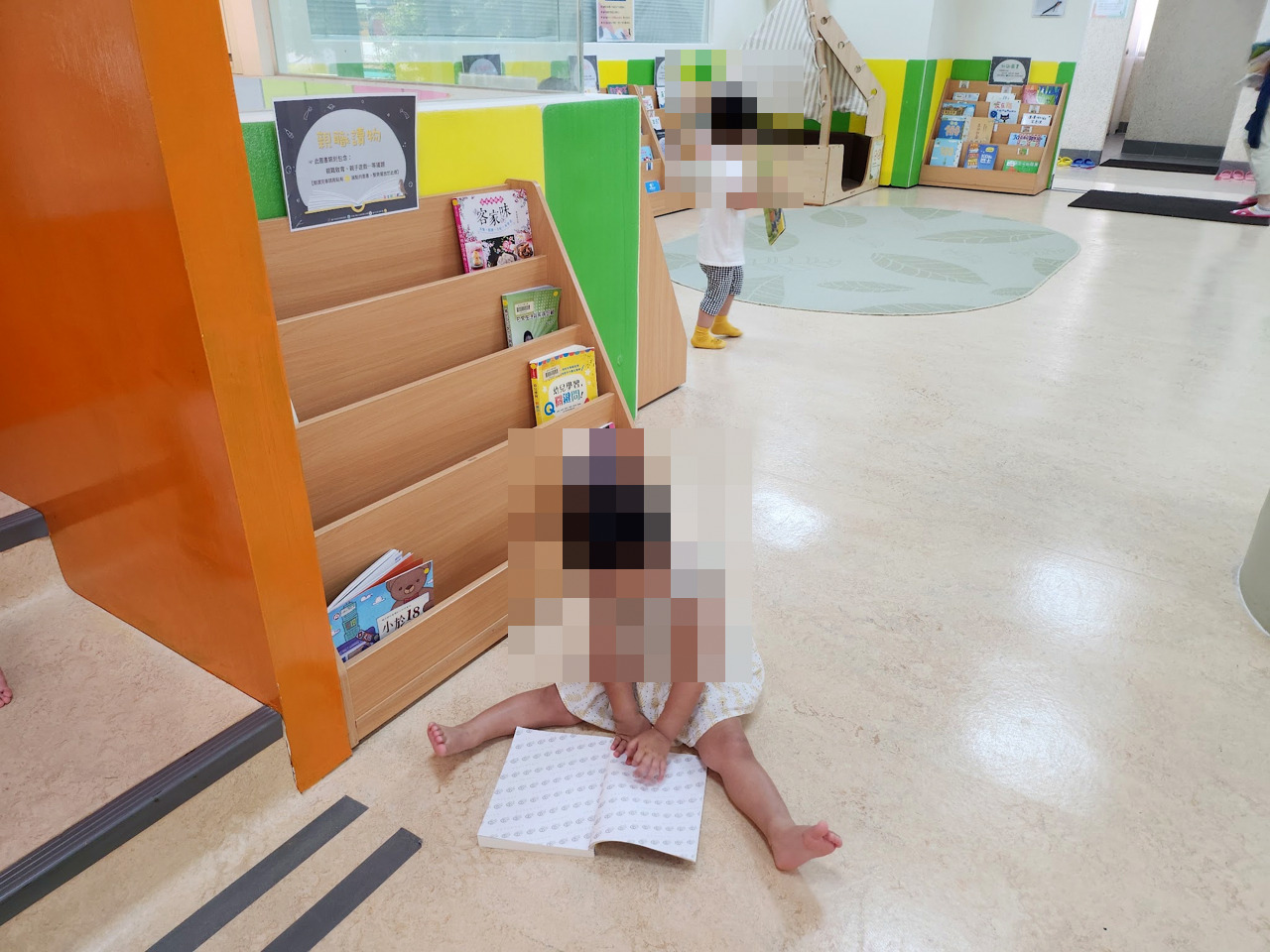 繪本區的書架旁,孩子坐在地上翻書