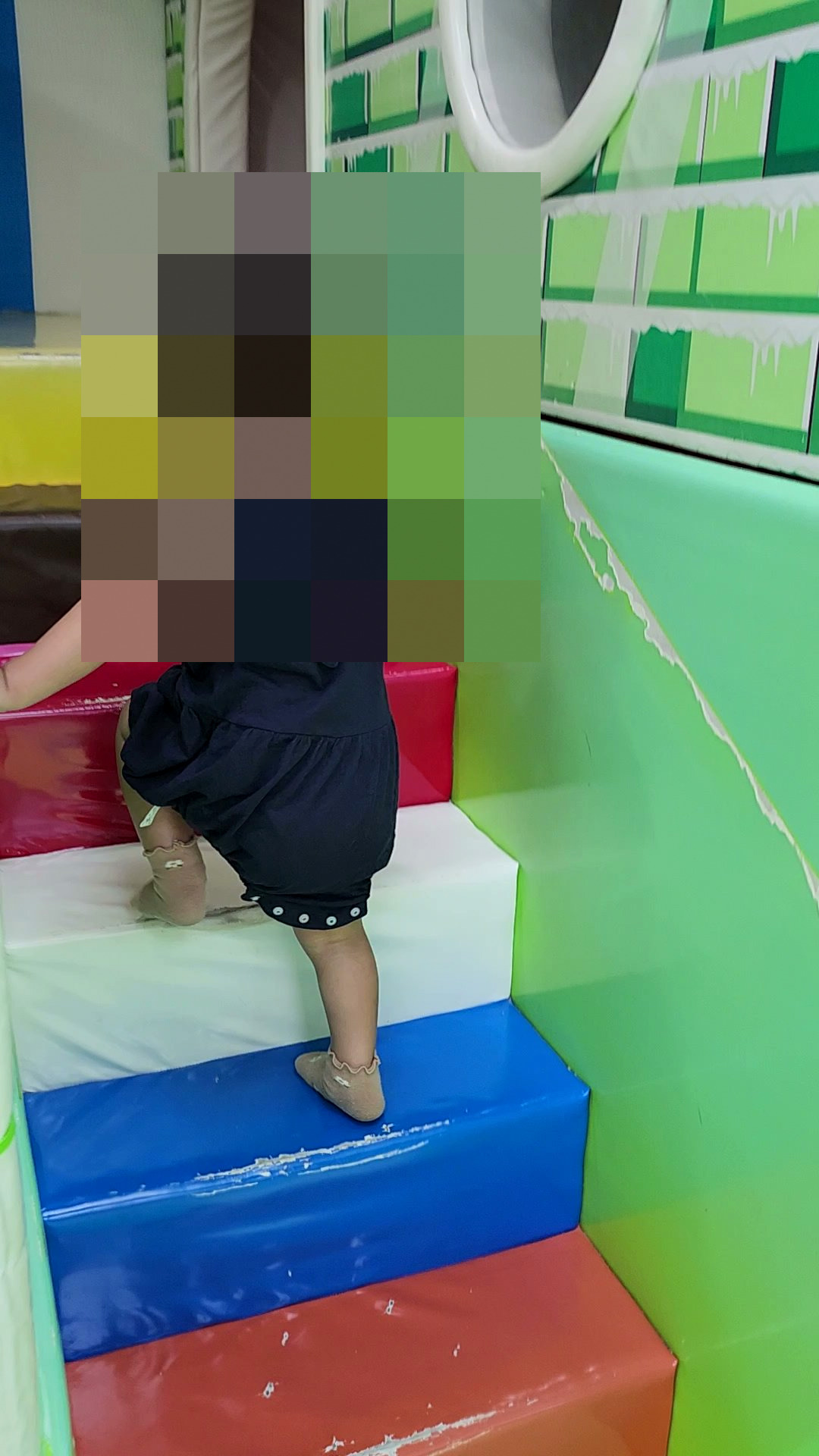 孩子赤腳踩上兒童遊戲區的彩色軟墊樓梯