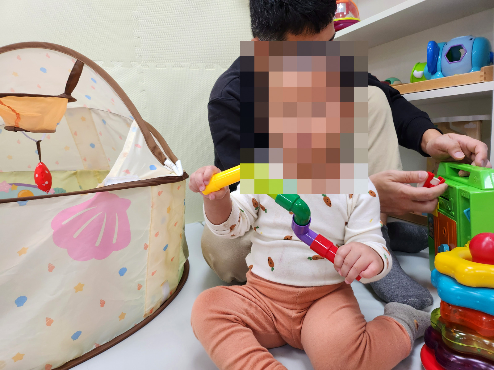 竹南親子館球池帳篷旁,寶寶拿著彩色玩具玩